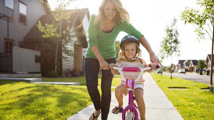 妈妈教小女儿学骑自行车.