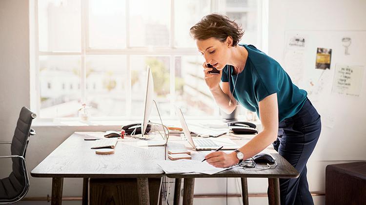 Woman working at a desk and talking on the phone.